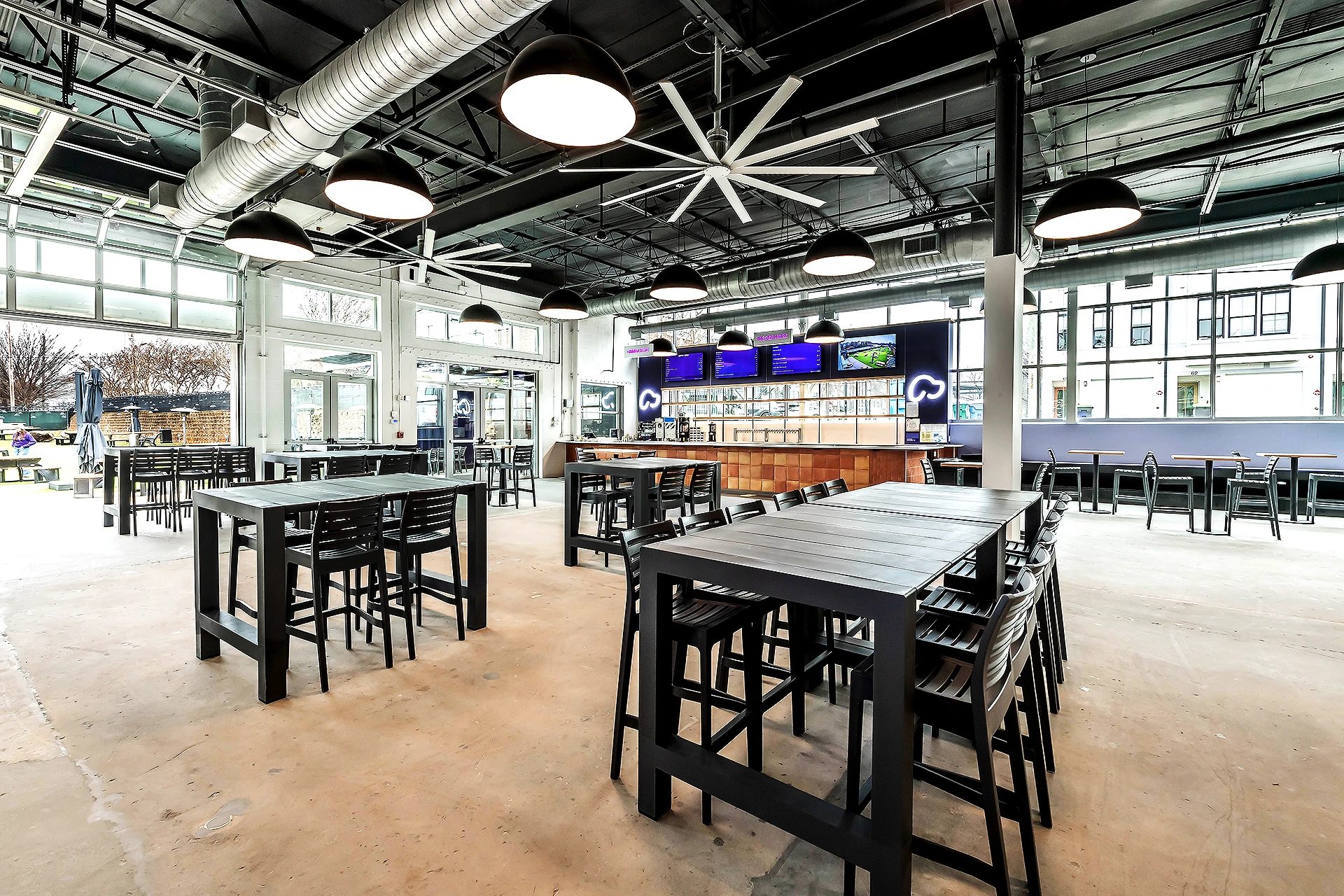 Skiptown Pet Facility Social Bar Area – Commercial Pet Facility Construction by BuiltByCCG Modern social bar area with high-top tables, exposed ceiling, and large windows in Skiptown pet facility built by BuiltByCCG commercial contractors in East Atlanta