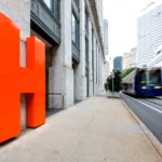 Modern building entrance renovation by Cornerstone, commercial construction company Atlanta, with custom orange 'H' monument signage