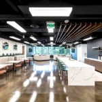 Lucid Pennant Park's modern break room featuring custom banquette seating, marble countertops, coffee bar, and designer lighting with floor-to-ceiling windows.