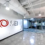 Sleek office entrance featuring SEI corporate logo in red and silver, modern glass doors, polished concrete floors, and exposed ceiling design in Atlanta commercial space