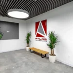 Modern reception area at Atlas Collaborative featuring architectural logo, wood slat ceiling design, custom LED lighting, and polished concrete floors by Cornerstone Contracting