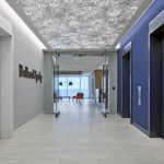 Modern office corridor featuring a decorative perforated ceiling, Ballard Spahr signage, and glass partitions showcasing premium commercial construction by CCG