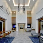 Two-story lobby featuring cascading pendant lights, textured wall panels, custom wood accents, and modern seating areas showcasing CCG's craftsmanship