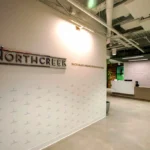Modern office reception area featuring dimensional signage, minimalist wall pattern, and concrete floors installed by CCG